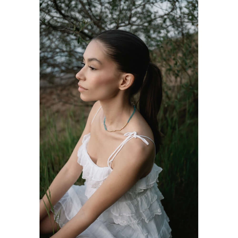 Младо момиче с колие Wave Син Тюркоаз, облечено в бяла рокля, на фона на природа.