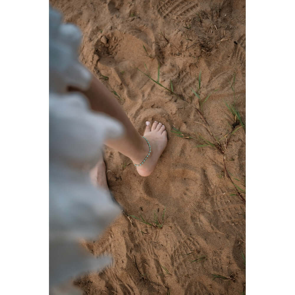 Гривна за глезен с сини мъниста, носена на пясъка, стилен бохо аксесоар, подходящ за лятото.